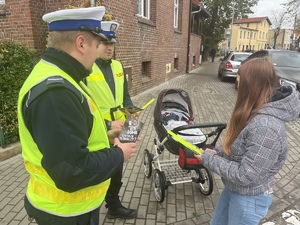 policjanci dający odblask kobiecie z wózkiem