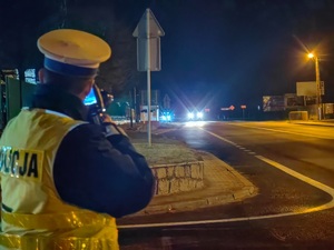 policjant podczas kontroli prędkości radarem po zmierzchu
